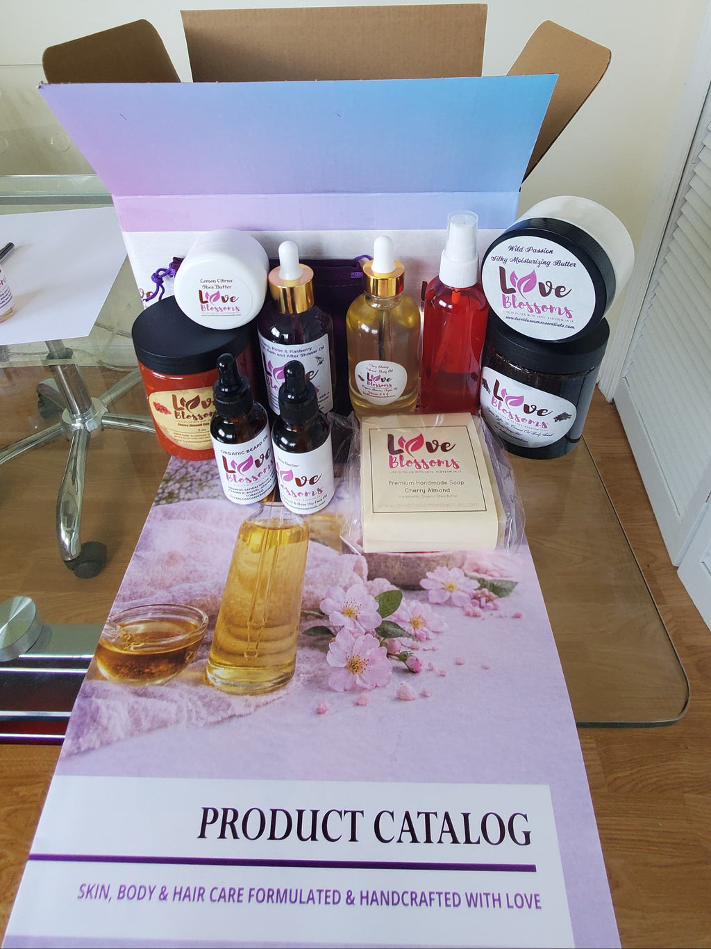 An open cardboard Brand Ambassador Starter Kit box filled with assorted hair, skin, and body care products from Love Blossoms Essentials.